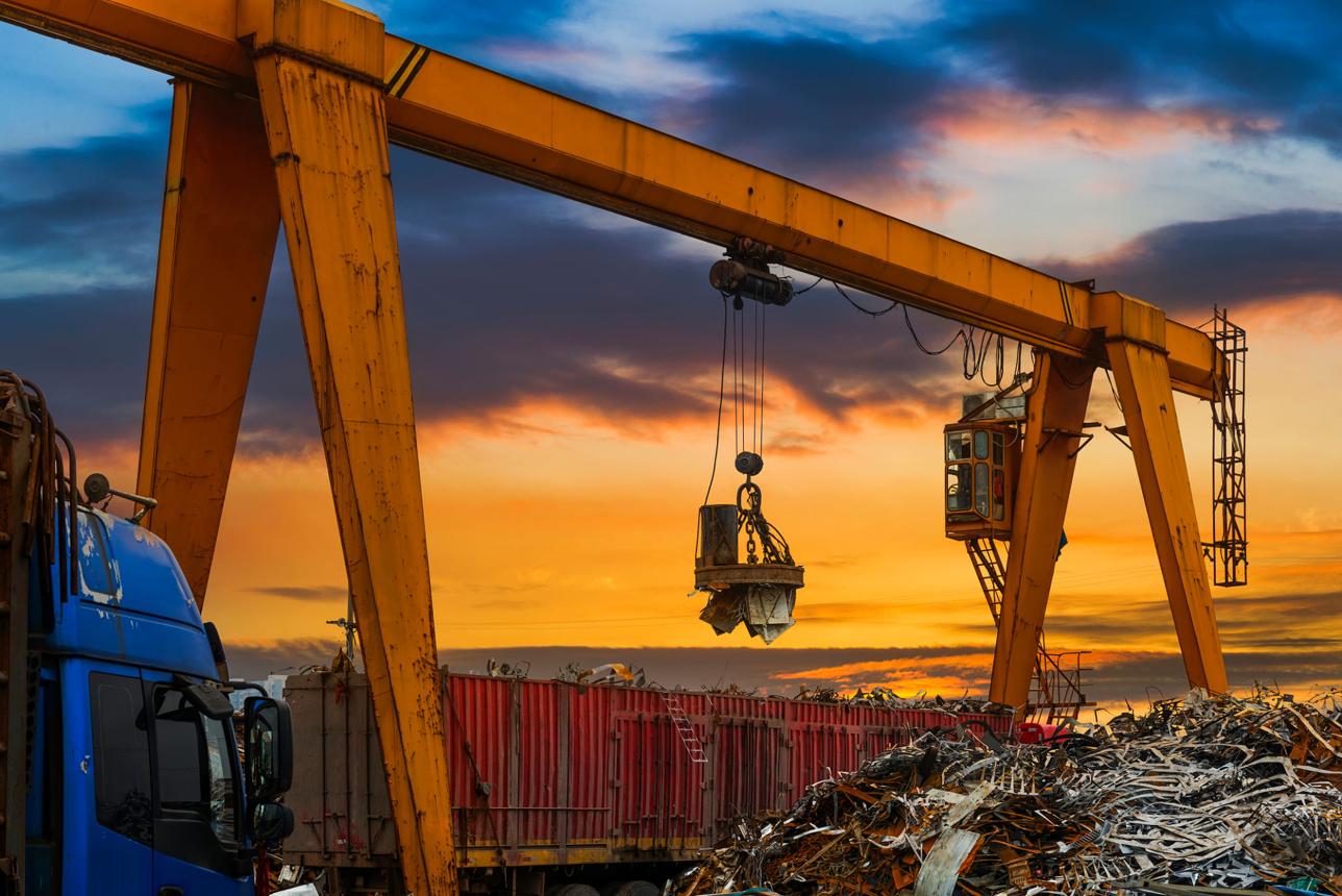 Scrap metal yard with an industrial crane at sunset